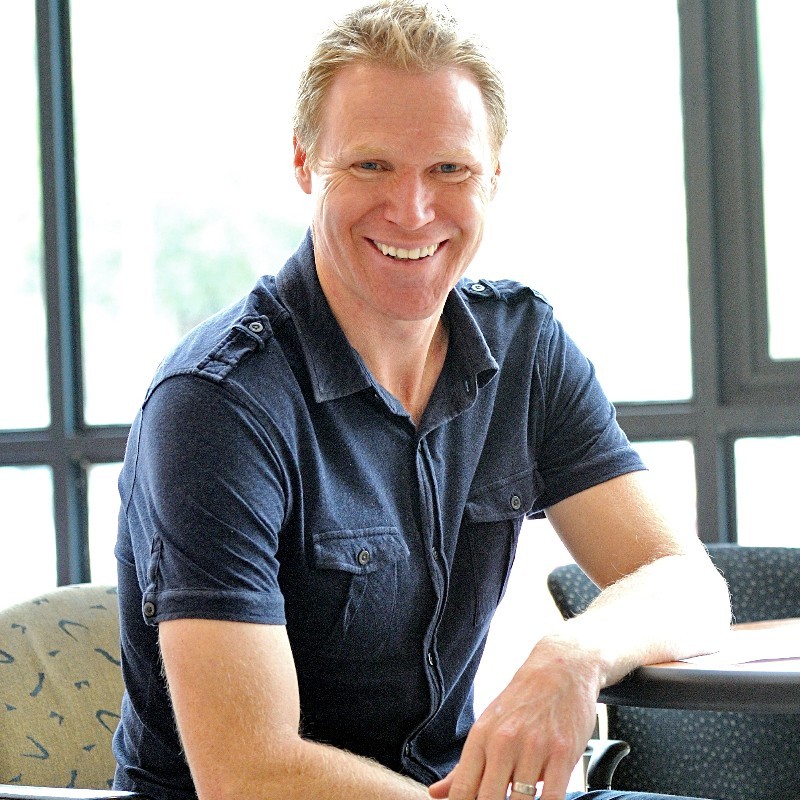 Profile image of Neil Hart sitting in a chair smiling at the camera